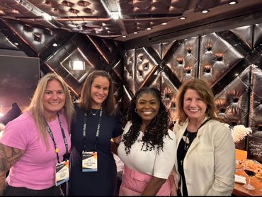 Four women smiling together at an event with Uber Eats badges in a stylish room.