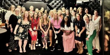 Group of women smiling for a photo indoors in a stylish setting.