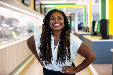 Smiling woman with long dreadlocks posing confidently indoors.
