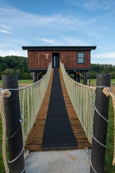 Custom log rope bridge provides a fun way to access your romantic treehouse getaway.
