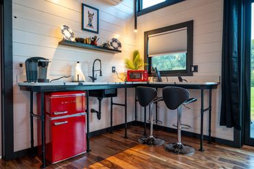 Modern Industrial kitchenette with bar stools, retro fridge & microwave, keurig, dishes & utensils.