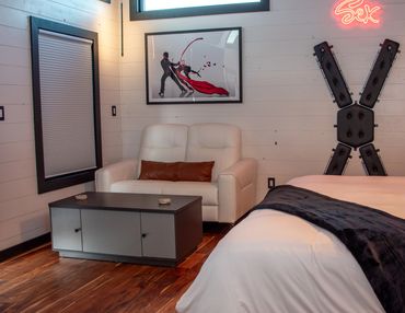 St. Andrews Cross for bondage, neon Sex sign, sexy artwork on wall and white leather loveseat.