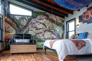 Bedroom & Living area with live oak mural on wall, comfortable leather loveseat & coffee table.