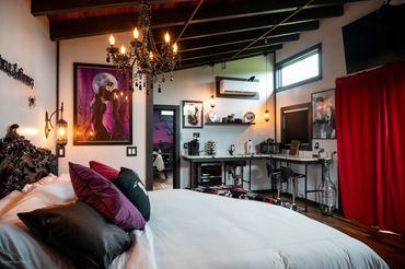 View of kitchenette w/ luxurious quartz countertop, bar stools, keurig, microwave, fridge, dishes.
