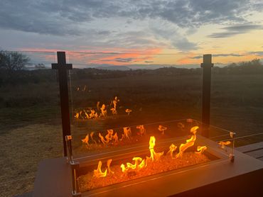 Linear gas firepit with sunset over mountains behind it.