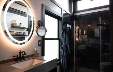 Luxurious bathroom w/ floating vanity, and dark large format tiles in shower, 10' rainfall head.