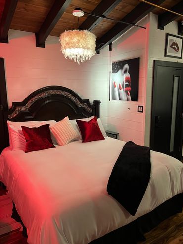 Luxurious king-sized bed with sexy artwork on wall.