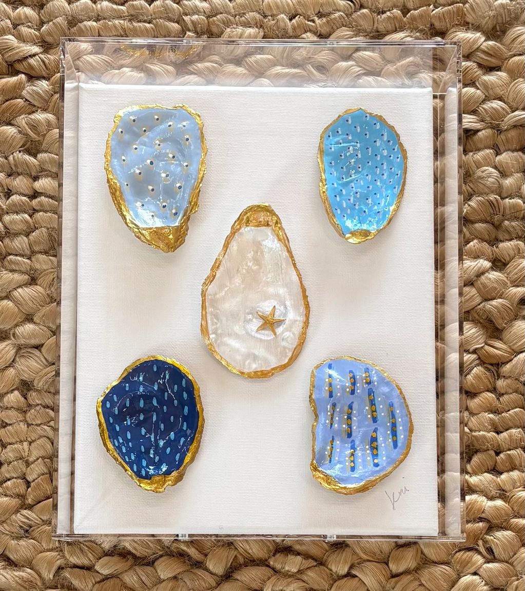 Artistic display of decorated seashells in a clear case.