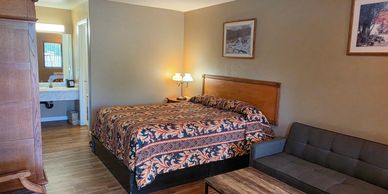 Cozy motel room with a bed, sofa, and wooden furniture.