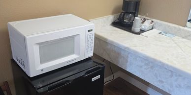 White microwave on a kitchen countertop next to a coffee maker and stove.
