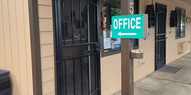 Green office sign with arrow on beige building exterior.
