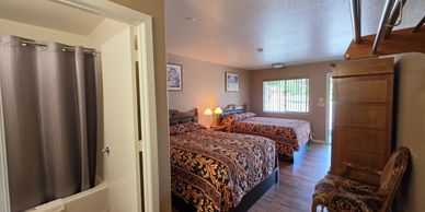 Cozy hotel room with two beds and a bathroom to the side.
