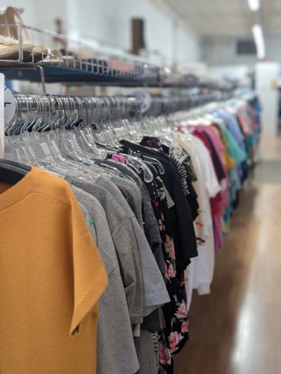 Clothes hanging on a rack in a store or thrift shop.
