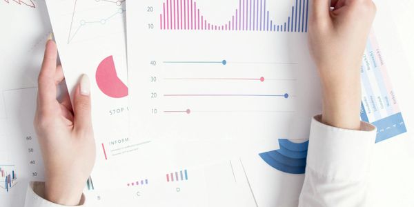 Hands holding and analyzing various colorful business charts and graphs.