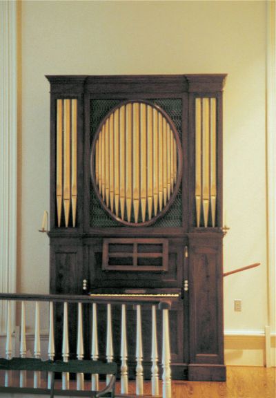 Antique pipe organ with wooden casing in a room.