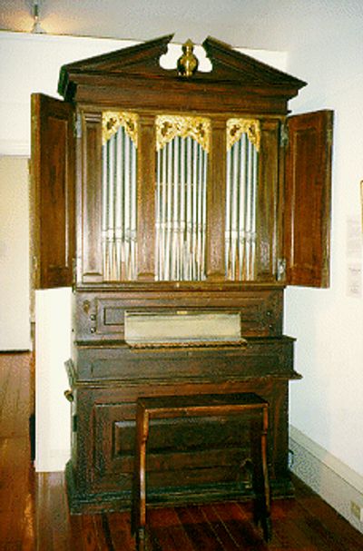 An antique pipe organ with wooden casing.