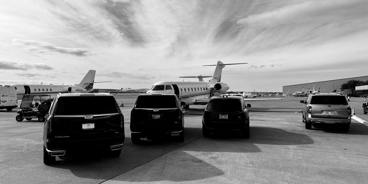 Black SUVs parked in front of a private jet on an airport tarmac.