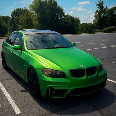 A vibrant green BMW parked in an empty lot on a sunny day.