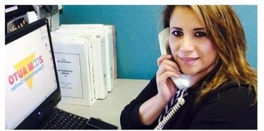 Woman talking on a phone at a desk with computer and files.
