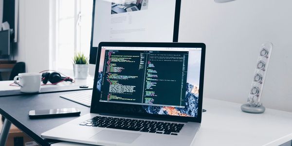 Laptop on a desk displaying coding scripts in a modern workspace.