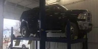 A black color car above the machine at repair shop