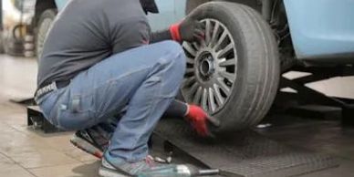 A man fixing the tire of a blue car