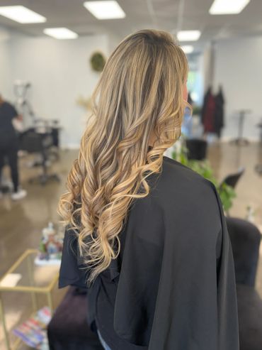 Blonde hair styled in soft curls at a salon.
