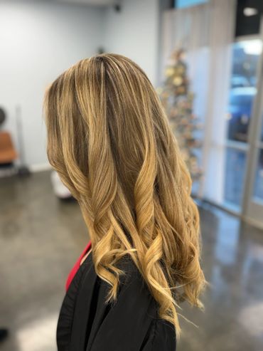 Blonde hair styled in loose curls with subtle highlights.
