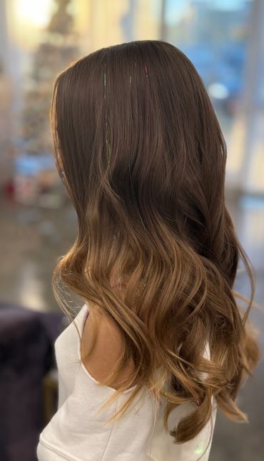 Woman with long, wavy brown hair and subtle highlights.