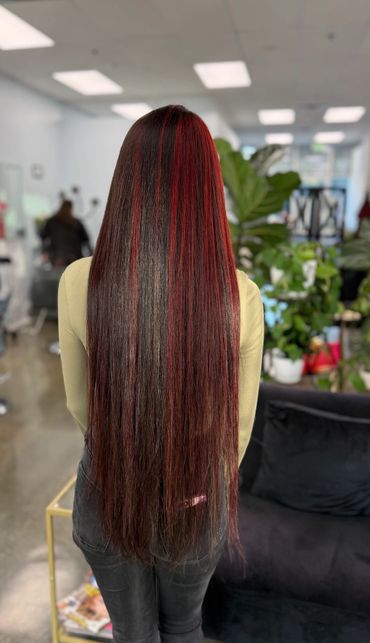 Long, straight hair with red highlights in a salon setting.
