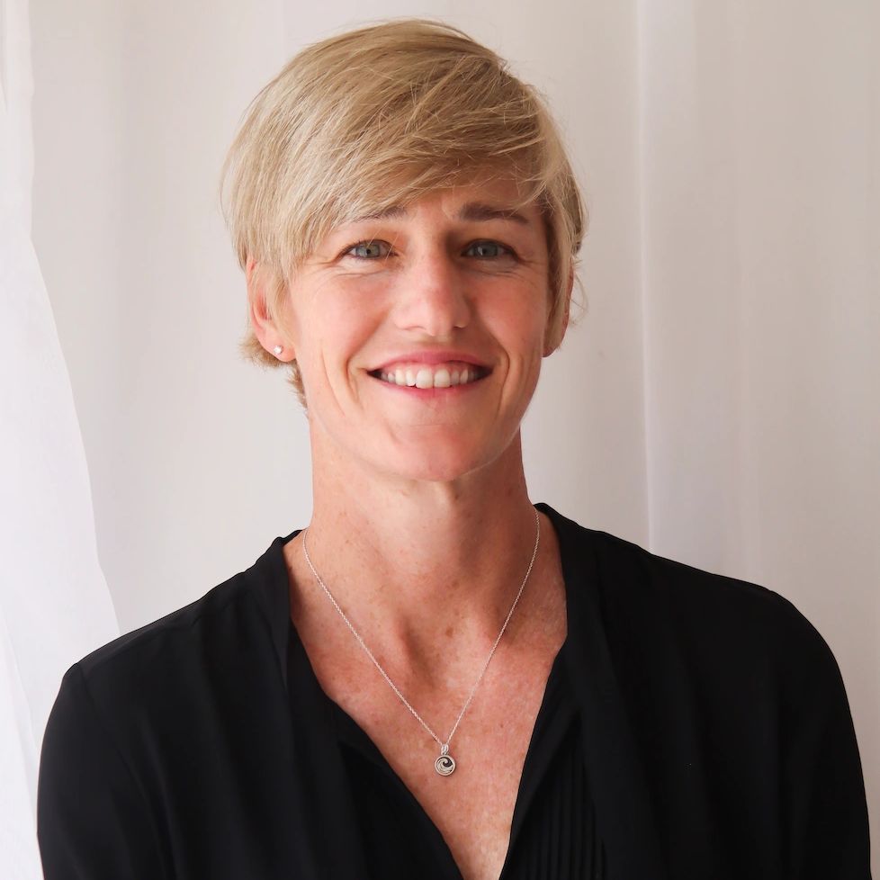 Smiling woman with short blonde hair and a black top.