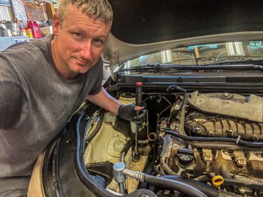 Man working on a car engine with a wrench in a garage.