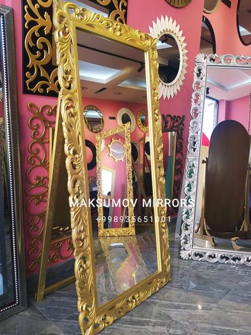 Ornate gold-framed standing mirror in a shop.