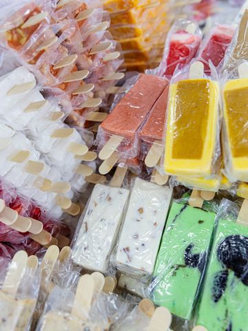 Colorful popsicles in plastic wrappers with various flavors and textures.