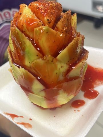 Pineapple carved like a flower with chili sauce and seasoning.