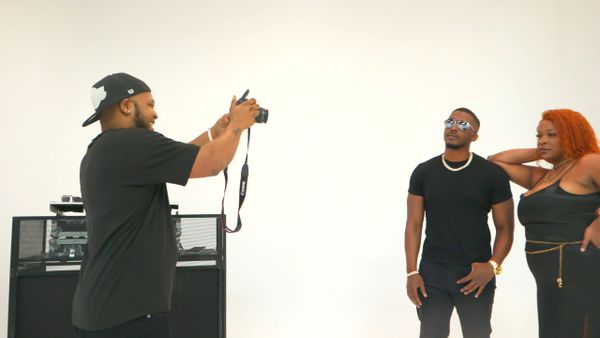 Photographer capturing a stylish couple against a white backdrop.