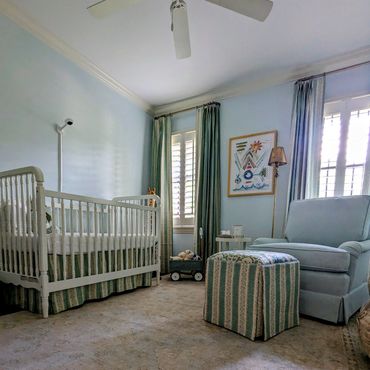 Cozy baby nursery with white crib, blue armchair, and striped ottoman.