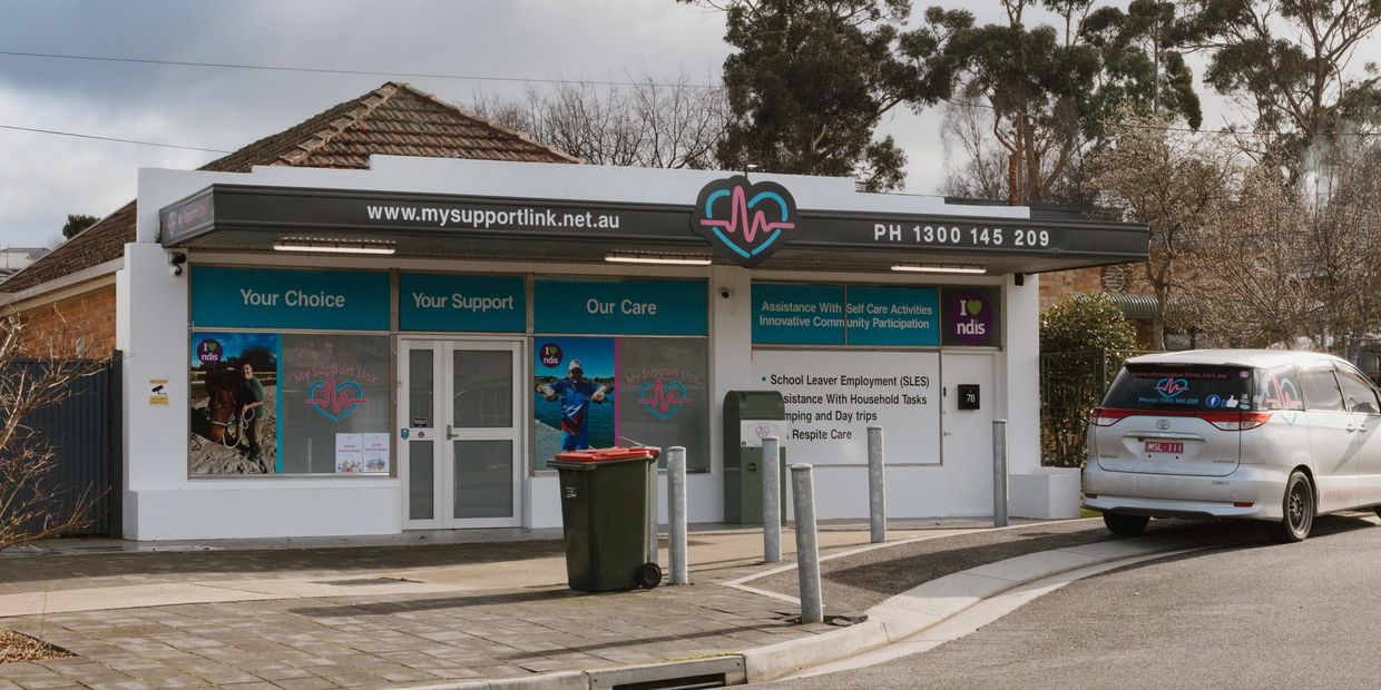 Support center building with signage and a parked van.