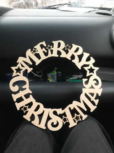 Wooden circular Christmas decoration with 'Merry Christmas' text and stars.