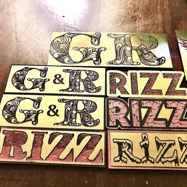 Various artistic wooden plaques with the words 'G & R' and 'RIZZ' in different styles.