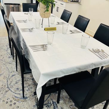 Elegant dining table set with white tablecloth and black chairs.