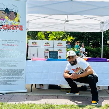 Man posing in front of a booth for Lil Chefs Culinary Kits outdoors.