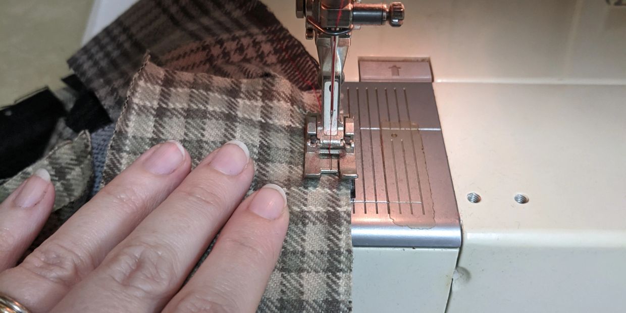 Close-up of sewing a plaid fabric with a sewing machine.