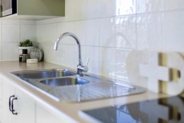 Modern kitchen sink with a chrome faucet and decorative items on the counter.