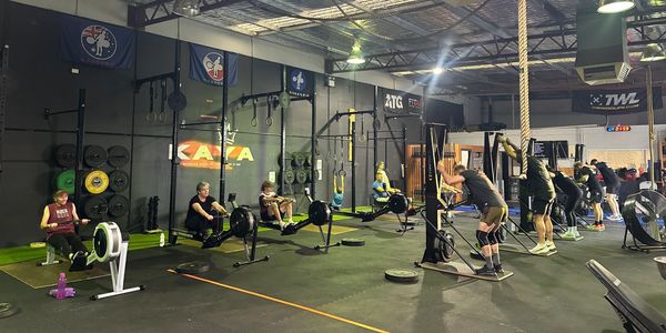 People exercising on rowing machines and ski ergometers in a gym.