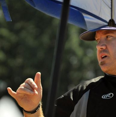 Man gesturing under an umbrella on a sunny day.