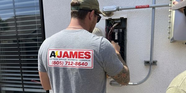 Electrician working on an electrical panel outdoors.