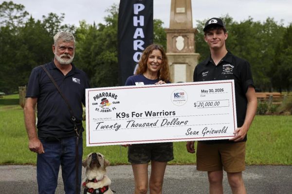 Three people and a dog holding a $20,000 donation check for K9s For Warriors.