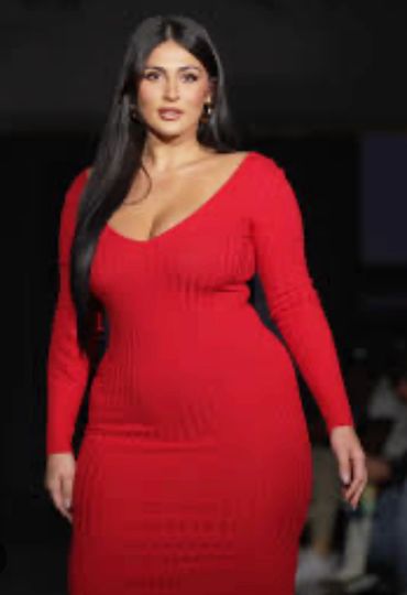 Woman confidently walking in a red dress on a runway.