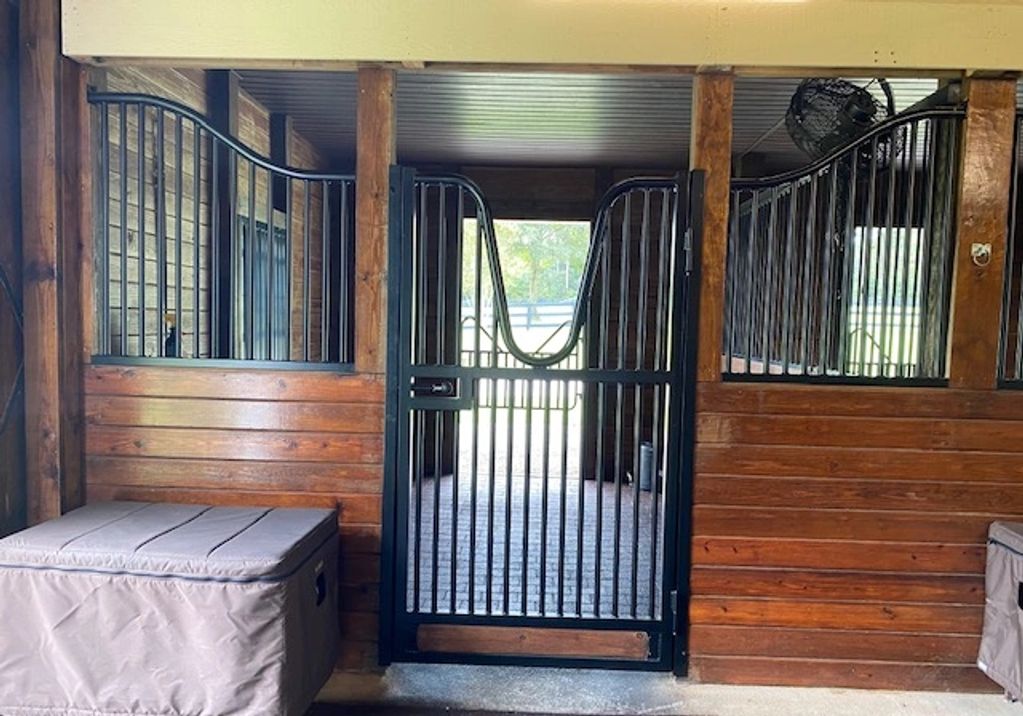 Horse stable with black metal gates and wooden walls.